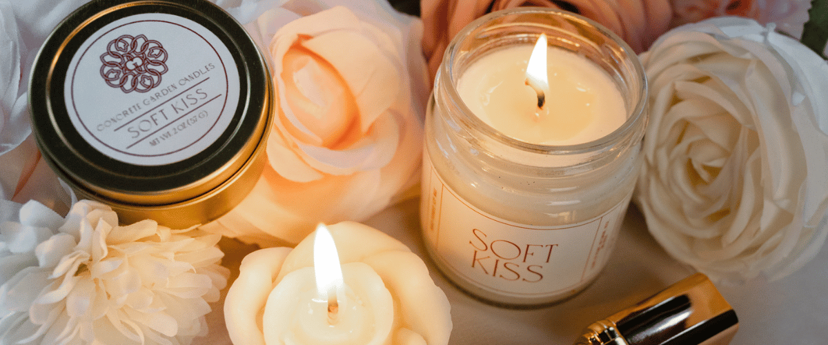 Natural Soy Wax Scented Candles lit with flowers and lipstick around them.
